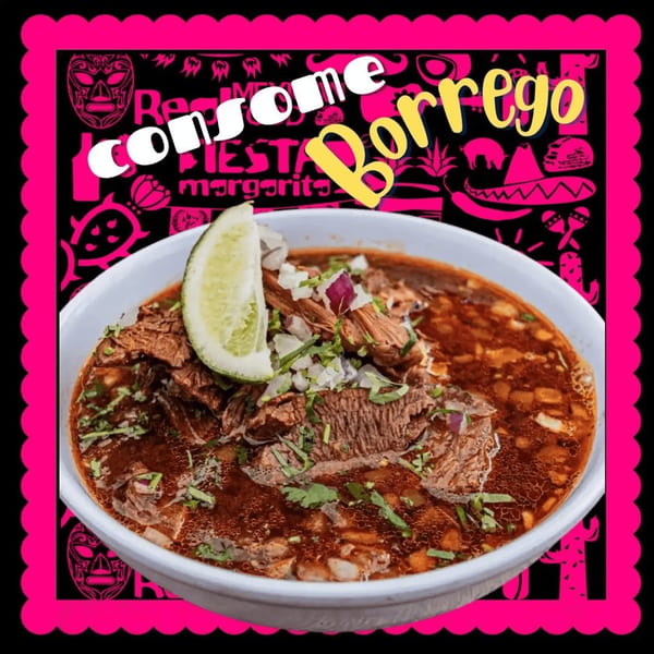 A bowl of Consome Borrego, a rich lamb stew, garnished with cilantro, onions, and a lime wedge.