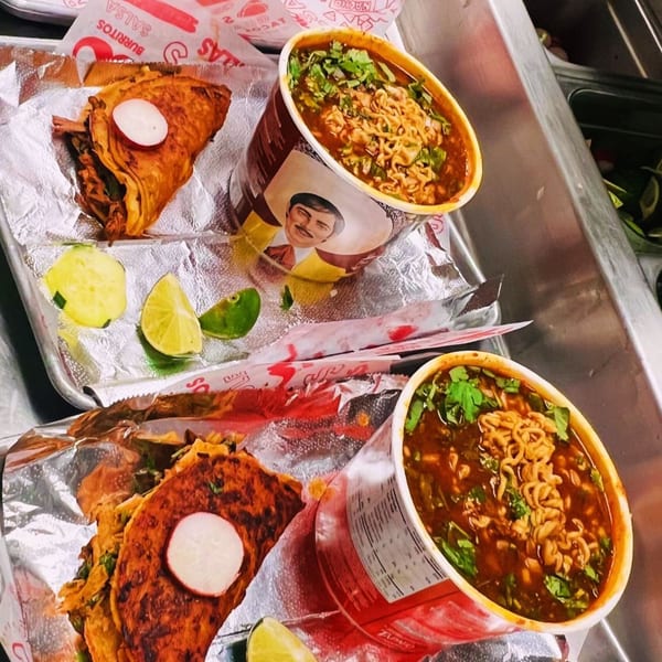 Two crispy tacos with radishes and two cups of ramen soup with cilantro on a metal tray.